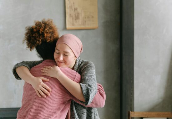 Women wearing head scarf hugging another woman